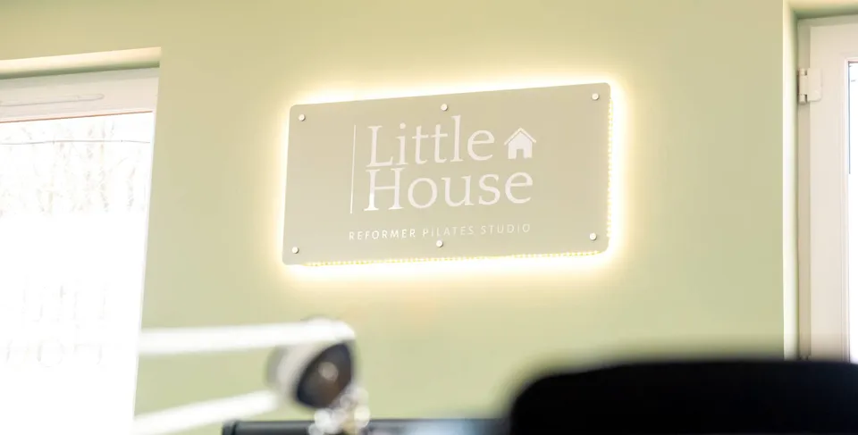 The illuminated Little House sign on the studio wall