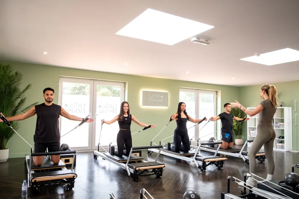 A group class working with the reformer straps, guided by an instructor